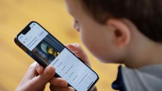 A boy plays with a mobile phone