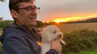 White poodle mix being held by Andy Burnham