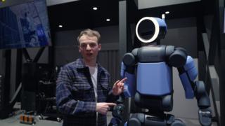 a-reporter-standing-with-a-humanoid-robot