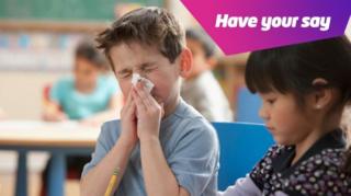 A boy blowing his nose in class.