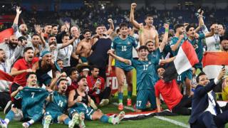 The Iraq squad celebrate on the pitch after sealing World Cup qualification