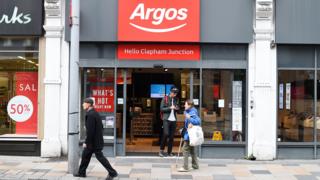 An Argos storefront in Clapham Junction. A young man is walking out of the shop while two people walk past it.