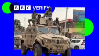 RSF fighters ride on an armoured truck in the city of Nyala. One of the fighters is carrying an assault rifle. All are dressed in military fatigues.