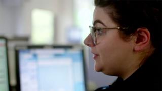 Photograph of Emily, an ambulance dispatcher, on a computer system at work.