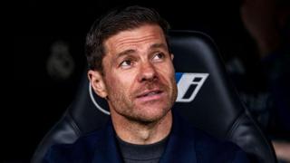 Xabi Alonso smiling while sat in the Real Madrid dugout
