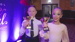 young ballroom dancing couple holding trophies