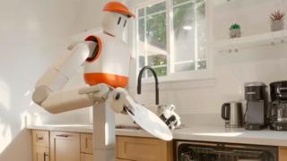 Sunday AI's Memo robot holds a plate in the kitchen and prepares to place it in the dishwasher