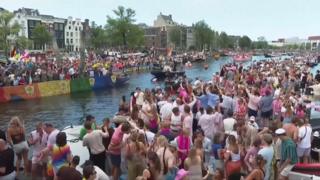 Revellers line Amsterdam canal to watch the annual Pride boat parade