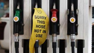 Petrol dispensers at a petrol station. One has a sign reading "sorry this hose is not in use".