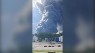 Huge plume of dark smoke rises from the horizon