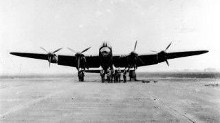 A black and white front-on image of a Lancaster Bomber preparing for takeoff at RAF Bottesford. Serviceman line-up in front of the plane near to the propeller blades on each wing