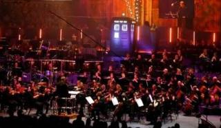 Colour image of an orchestra with the TARDIS in the background