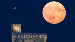 A large moon shining in a clear sky over Windsor Castle