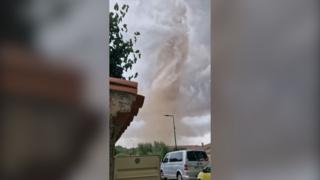 Image of a tornado with a car in the foreground.