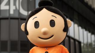 A person wearing a Sali Mali costume, standing outside the S4C headquarters in Carmarthen.