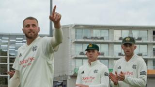 Fergus O'Neill points to someone in the crowd as he leaves the pitch with two team-mates behind him, both applauding