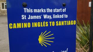 A blue sign that reads 'This marks the start of St James' Way, linked to Camino Ingles to Santiago'