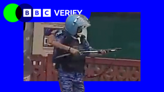 A still from a video of a rapid action force officer in Delhi, raising what experts say is a pellet gun.
