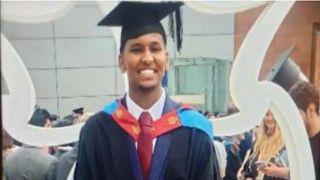 Badri Issa smiles into the camera at a university graduation ceremony.