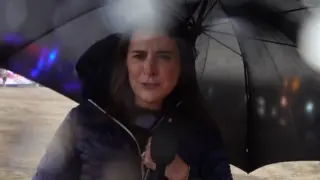 Reporter under an umbrella.