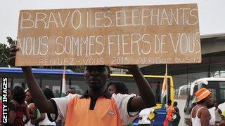 An Ivory Coast fan holds a sign which says he and his colleagues are proud of their team