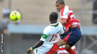 Liberia's Barshall Cele rises above new Senegal Papiss Demba Cisse, who missed an early penalty