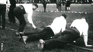 A tug of war team have their boots inspected, 1912