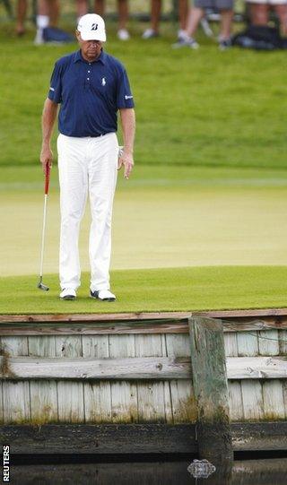 Davis Love III surveys an alligator in the water on the 17th hole