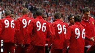 Liverpool players, wearing '96' on their tracksuits, shake hands with Manchester United players before kick-off