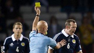 Scotland's Charlie Adam is booked by referee Sergey Karasev