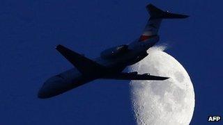 A commercial plane flying in front of the moon