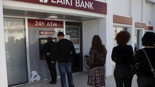 Cypriots queue at a cash-machine