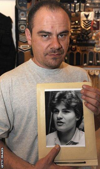 Former German shot putter Andreas Krieger, who competed as a woman (Heidi Krieger) on the East German athletics team, poses with a picture of himself in 1987