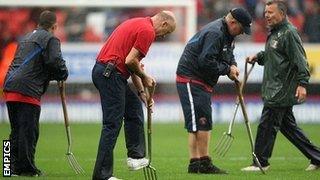 Groundstaff tend to the sodden playing surface at the The Valley