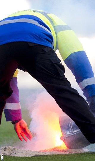 A Falkirk steward douses the flames of a flare on the pitch on Saturday