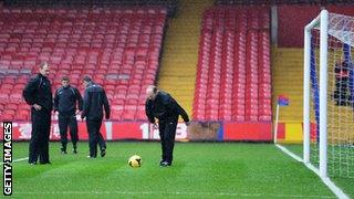 Referee Mike Dean checks the condition of the pitch before Crystal Palace host Norwich