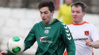 Owain Beggs of Dundela shields the ball from Carrick's Ryan McCann