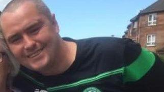 Pic of Allan Doris leaning into towards the camera, smiling and wearing a Celtic football top