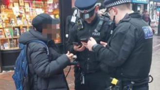 Two police officers stop a youth riding an electric scooter through Chatham's pedestrianised zone.