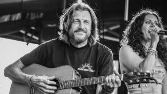 Blue Reef Festival organiser on stage playing guitar with a female singer