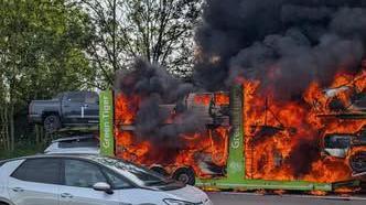 A view of a car transport ablaze from the other side of the motorway