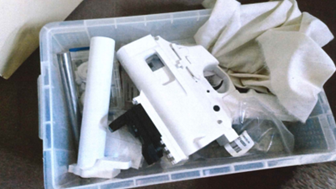 A plastic container with parts of a gun manufactured on a 3D printer