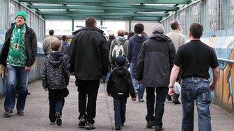 Fans cross over the old railway bridge on their way to the match at Windsor Park