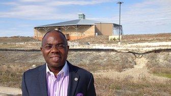 Pastor James Fadele stands in front of a church being built in Floyd, Texas