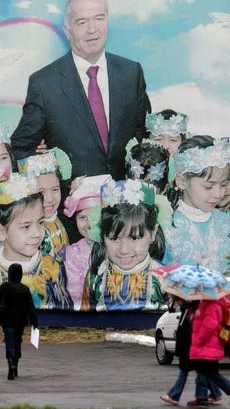 People walk in front of a giant poster of Uzbek President Islam Karimov in Tashkent, 24 December 2007.