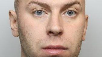 Police mugshot of Cameron Evans, who has blue eyes and shaved brown hair.