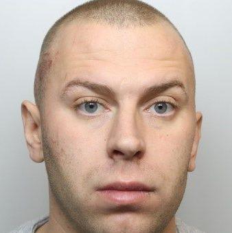 Police mugshot of Cameron Evans, who has blue eyes and shaved brown hair.