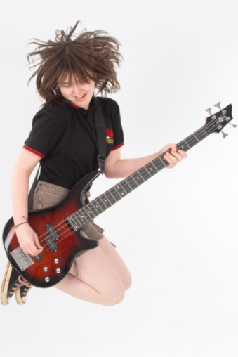Teenage girl with brown hair is jumping with her electric guitar.
