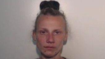 Grainy custody shot of defendant whose brown hair is in a bun.