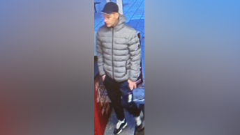 A CCTV image of a man in a navy baseball cap, grey jacket and skinny-fit tracksuit bottoms. 